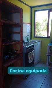 a kitchen with a stove and a window at Cabañas Las Murallas in Punta de Choros