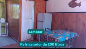 a kitchen with a table and a refrigerator in a room at Cabañas Las Murallas in Punta de Choros