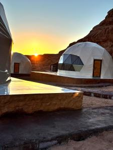 un gruppo di tende nel deserto con il tramonto di Nara desert camp a Wadi Rum