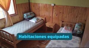 a room with two beds in a wooden cabin at Cabañas Las Murallas in Punta de Choros