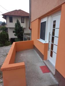 een oranje gebouw met een bank voor een deur bij KIM in Sarajevo