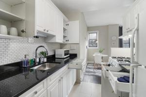 una cocina con armarios blancos y encimeras negras en Enchanting 1BR Urban Retreat in Hyde Park - Windermere 401, en Chicago