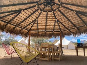 a wooden table and chairs under a straw umbrella at Camper with A/C - Glamping 3 Idiomas in El Sargento