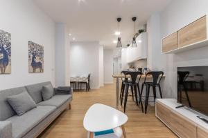 a living room with a gray couch and a kitchen at Gran apto a 5 min de casco viejo. Familias, grupos in Bilbao