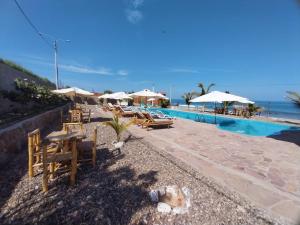 um resort com piscina, mesas e guarda-sóis em Casuarinas del Mar Hospedaje Habitacion Cerro 1 em Canoas de Punta Sal