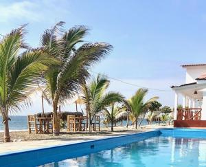uma piscina ao lado de uma praia com palmeiras em Casuarinas del Mar Hospedaje Habitacion Cerro 1 em Canoas de Punta Sal