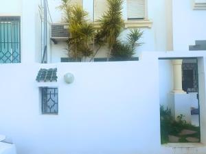 een wit huis met palmbomen ervoor bij Duplex Familial 2 Chambres 131m2 avec Jardin Privé - Service Aéroport - Internet Fibre Optique in Borj Turki