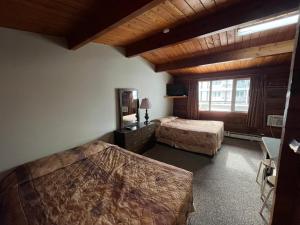 Habitación de hotel con 2 camas y ventana en Raccoon Lodge Motel, en Sylvan Lake