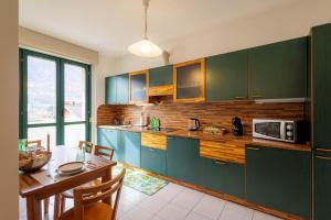 ソンドリオにあるRevo Apartments - Quadrifoglioのキッチン(緑のキャビネット、ダイニングルーム付きのテーブル付)