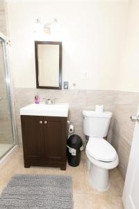 a bathroom with a toilet and a sink and a mirror at Bright 2-Bed Haven Close to NYC in Jersey City