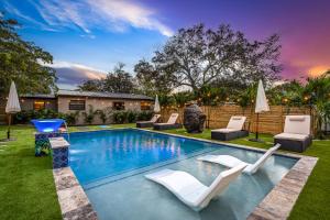 uma piscina com cadeiras brancas e um quintal em Bali Inspired home with Heated Pool, Sauna and Hot Tub! Close to Beach and Atlantic Ave em Delray Beach