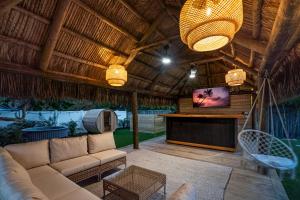 uma sala de estar com um sofá e uma televisão num pátio em Bali Inspired home with Heated Pool, Sauna and Hot Tub! Close to Beach and Atlantic Ave em Delray Beach