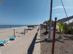 einen Sandstrand mit Liegestühlen und das Meer in der Unterkunft Casuarinas del Mar Habitacion Cerro 2 in Canoas De Punta Sal