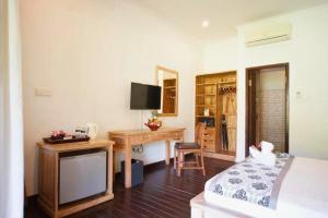 a bedroom with a bed and a desk and a television at Sidesratra 1 BR Classic Superior NE56 in Gili Islands