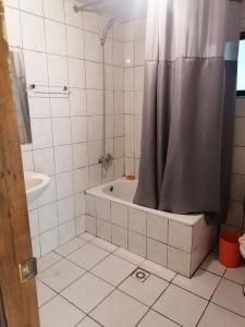 ein Bad mit einer Badewanne und einer Dusche mit einem Duschvorhang in der Unterkunft Cisnes del tolten in Freire