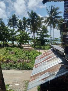 a rusty roof of a building with palm trees in the background at sharkbunkbed siargao in General Luna