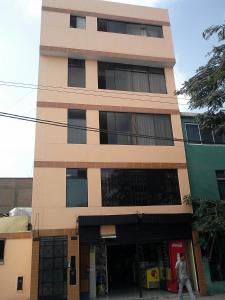 un edificio alto con un hombre caminando delante de él en Hostal Jovita, en Lima