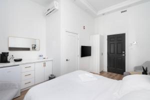 a white bedroom with a white bed and a black door at Penfield Suites in Montreal