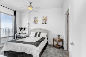 a white bedroom with a bed and a window at Downtown Tampa Gem 1-BD w/Pool, Gym, & Sky Lounge in Tampa