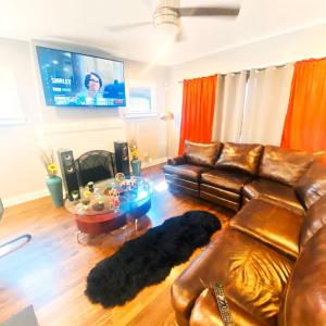 a living room with a leather couch and a flat screen tv at Fully Equipped Cozy 4/5 BR in Chicago