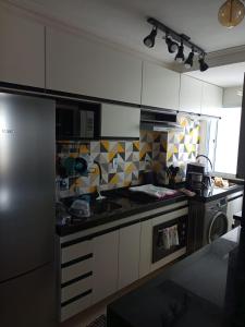 eine Küche mit weißen Schränken und einer schwarzen Arbeitsplatte in der Unterkunft AP do Brian in São João del Rei