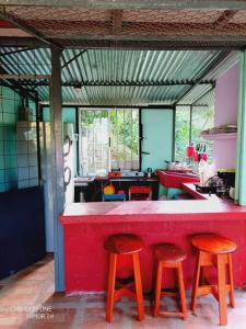eine Küche mit einer roten Theke und 3 Hockern in der Unterkunft Cabaña con piscina in Venecia