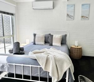 a bedroom with a bed with blue sheets and pillows at Driftwood Townhouse - Waterfront-Central Location in Lakes Entrance