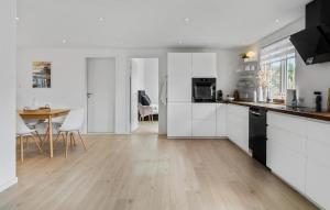 een keuken met witte kasten en een houten vloer bij Stunning Home In Melby With Kitchen in Melby
