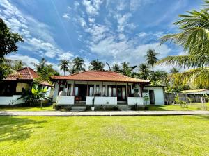 a house with a lawn and palm trees at Tejakula Sunset Boutique Resort in Tejakula