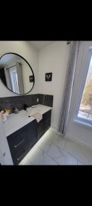 a bathroom with a sink and a mirror and a window at L'hêtre au Sommet (gîte) in Sainte Anne des Lacs