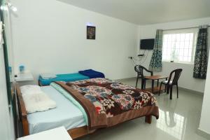 Schlafzimmer mit einem Bett, einem Tisch und Stühlen in der Unterkunft dreams cottage in Udagamandalam