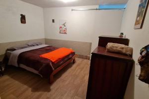a bedroom with a bed with an orange pillow on it at Hospedaje Las Bromelias - Mini Departamento in Papallacta