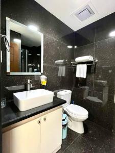 a bathroom with a sink and a toilet and a mirror at Sheryll Escapes - 214 La Grande Studio, comfy hotel amenities with Netflix! in Angeles