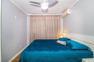 a bedroom with a blue bed and a ceiling fan at APTO 2 DORM PRÓXIMO CONSULADO AMERICANO, FIERGS, C0MPLETO E GARAGEM in Porto Alegre