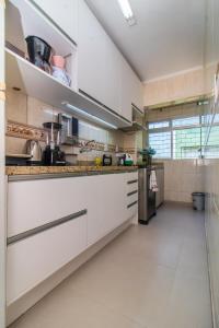 a large kitchen with white cabinets and appliances at APTO 2 DORM PRÓXIMO CONSULADO AMERICANO, FIERGS, C0MPLETO E GARAGEM in Porto Alegre