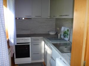 a kitchen with white cabinets and a sink and a stove at Am Schlierbach in Unterwössen