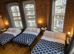 two beds in a room with two windows at Midtown Nest Loft Studio in New York