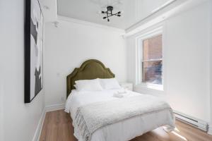 a white bedroom with a bed and a window at Penfield Suites in Montréal