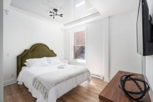 een witte slaapkamer met een bed en een televisie bij Penfield Suites in Montreal