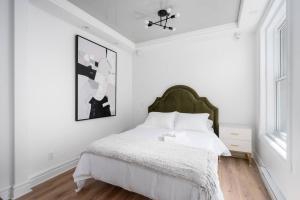 モントリオールにあるPenfield Suitesの白いベッドルーム(緑のヘッドボード付きのベッド1台付)