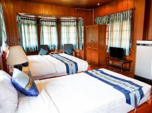 um quarto de hotel com duas camas e uma televisão em Malulee Homestay/Cafe/Massage em Lampang