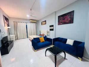 Studio Apartment في عجمان: غرفة معيشة مع أريكة زرقاء وطاولة