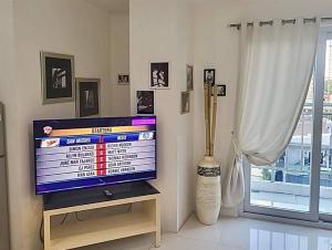 a television sitting on a stand in a living room at Sheryll Escapes - Kandi big studio l balcony l housekeeping l Netflix in Angeles