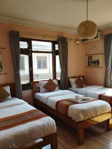 3 camas en una habitación con ventanas en Cloud 9 Garden en Katmandú