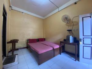 a small room with a bed and a table and a fan at Jogja Inn in Timuran