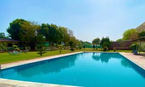 ein großer blauer Pool in einem Park in der Unterkunft Vanzara Retreat in Gurgaon