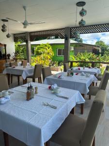 a dining room with white tables and white chairs at Benjamine's Guesthouse in La Digue