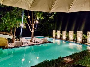 a swimming pool with lounge chairs and an umbrella at Dreamview Mountains - Cozy 1bhk with Sunrise view in Karjat