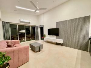a living room with a pink couch and a flat screen tv at Dreamview Mountains - Cozy 1bhk with Sunrise view in Karjat