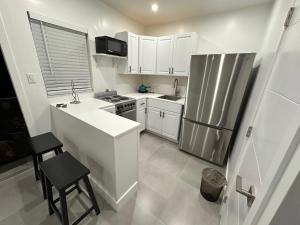 uma cozinha com armários brancos e um frigorífico de aço inoxidável em LYZ Miami Airport em Miami